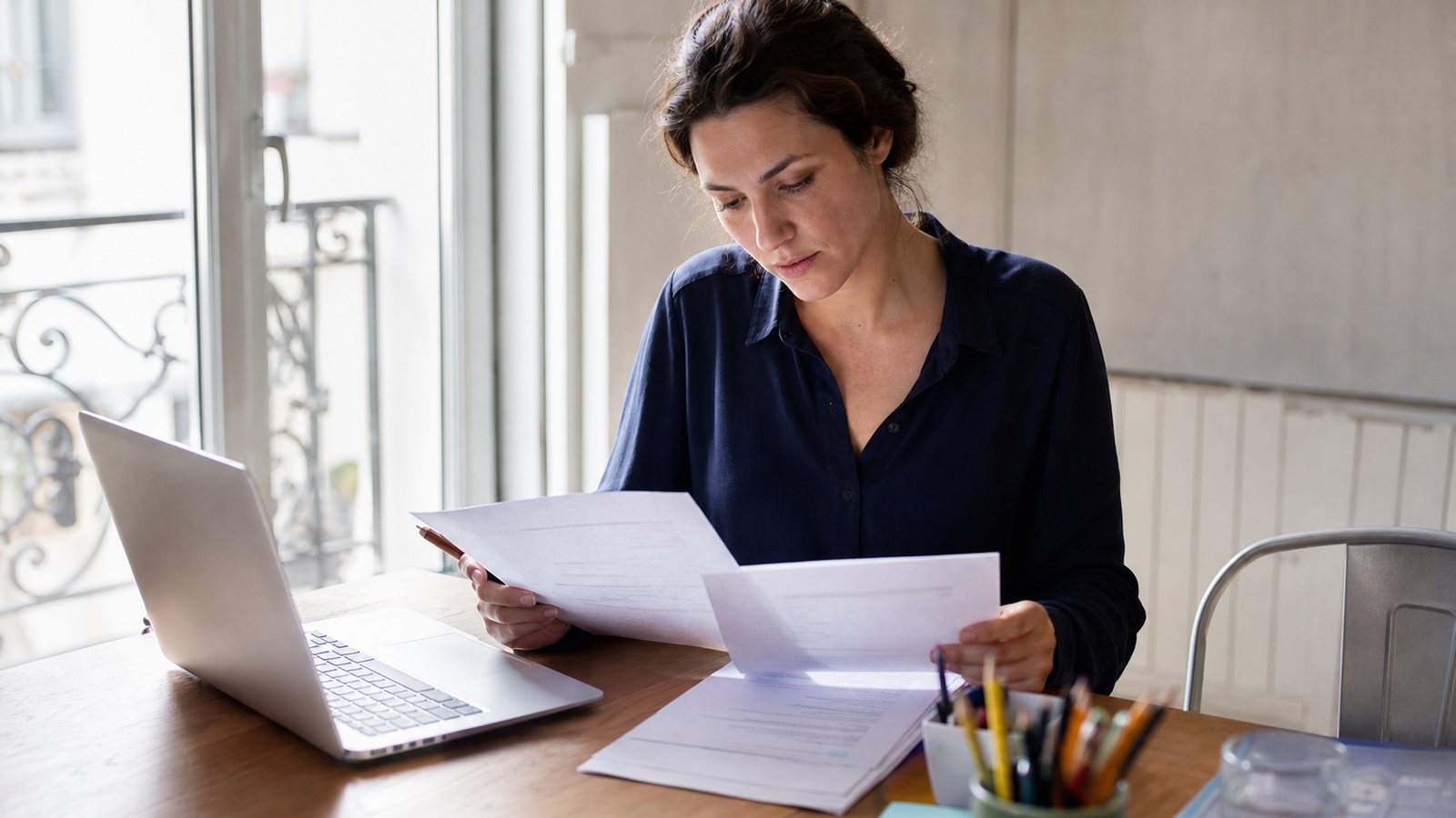 Auto-entrepreneur vérifiant les mentions obligatoires d'une facture sur son écran